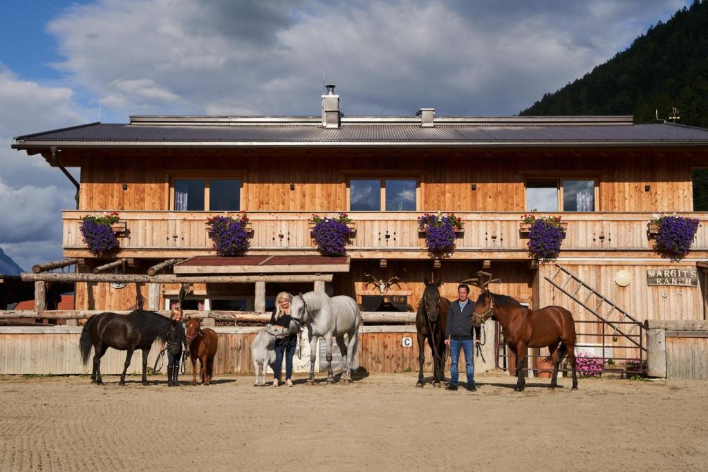 锡尔茨B&B Margit's Ranch Urlaub am Pferdehof的一群人站在一座有马的建筑前