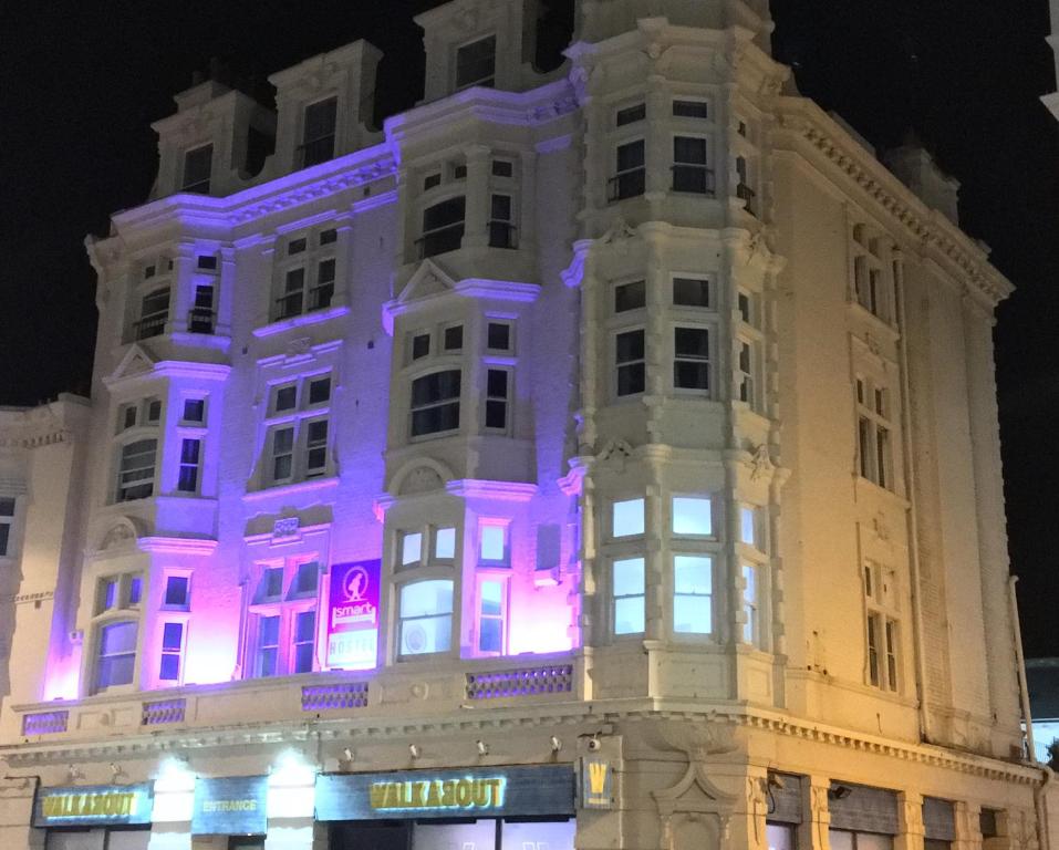 布莱顿霍夫Brighton Beach Inn的白色的建筑,上面有紫色的灯