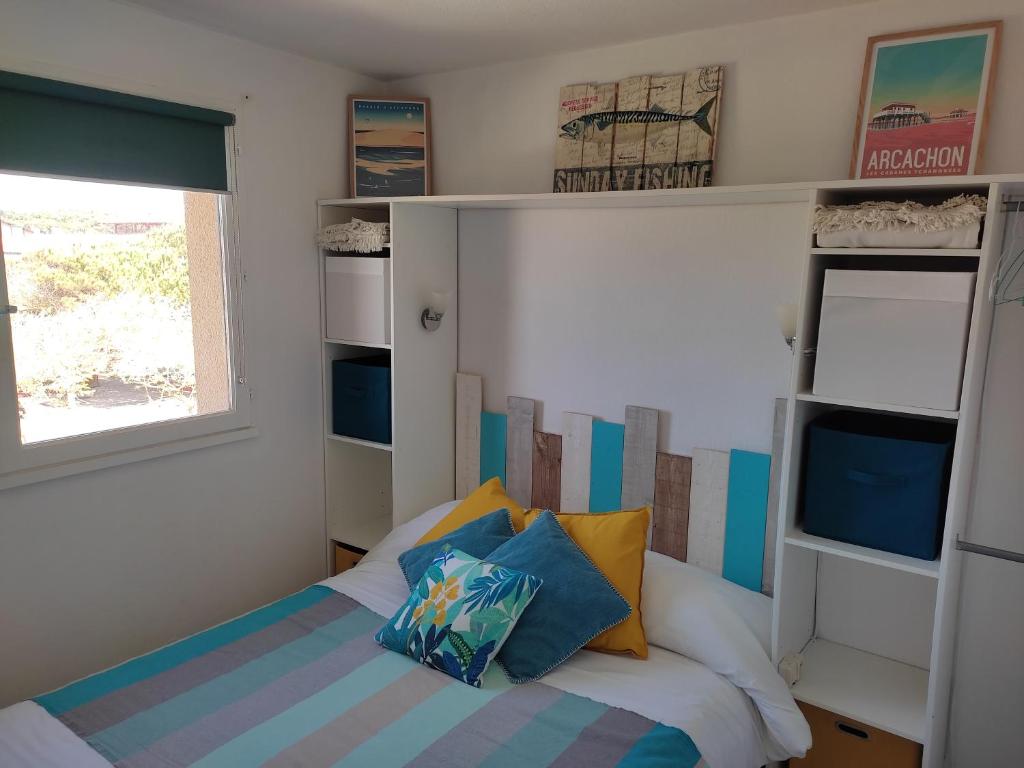 比斯卡罗斯海滩appartement T2 biscarosse plage的一间卧室设有床、窗户和书架