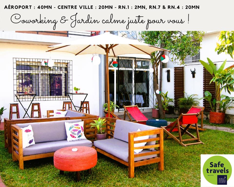 塔那那利佛Villa Mahefa - WIFI - Canal Plus - Terrasse & Jardin的天井配有2张沙发、遮阳伞和椅子
