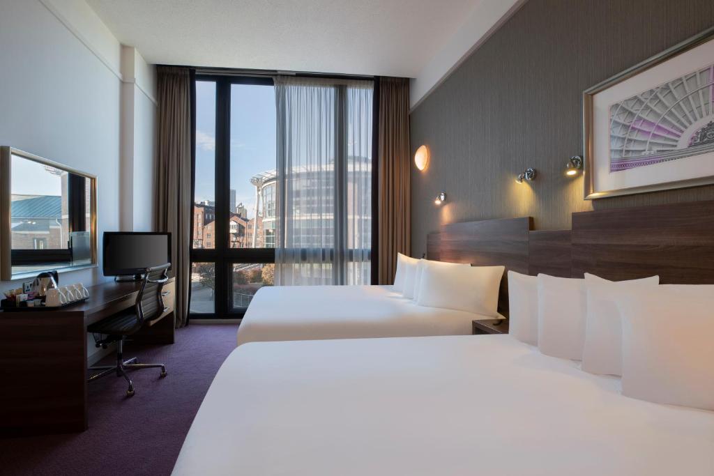 利兹Leonardo Hotel Leeds的酒店客房设有两张床和大窗户。