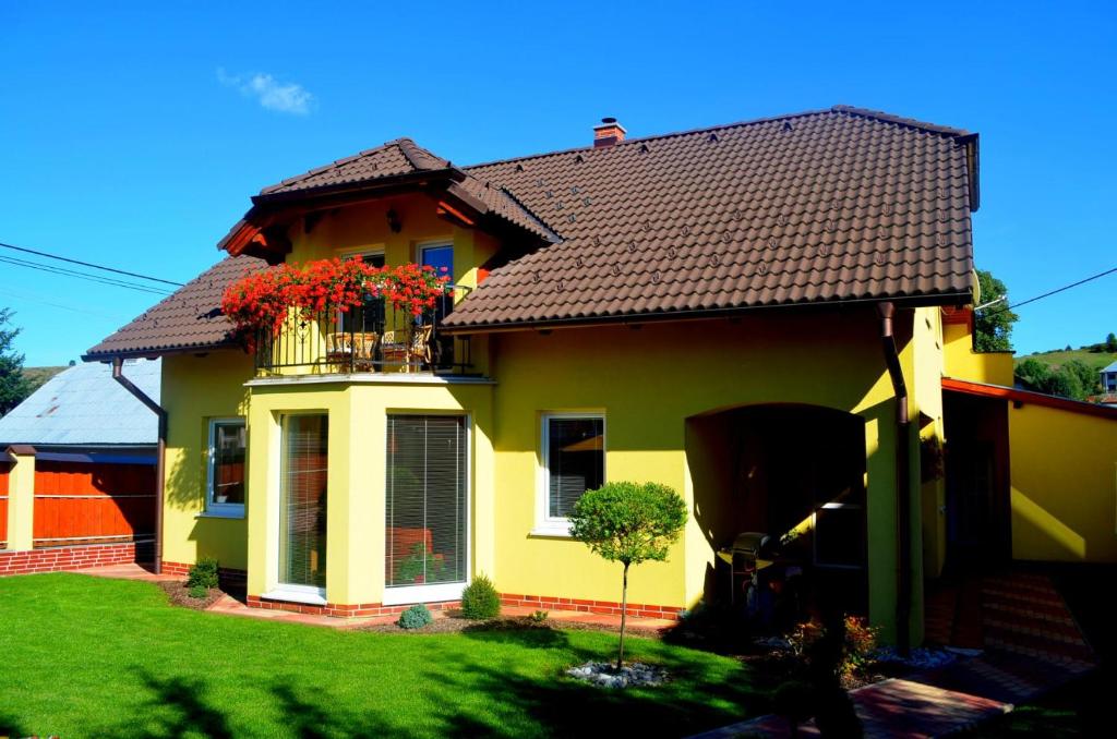 贝谢诺瓦Vila Deluxe - Liptov, Bešeňová的黄色的房子,阳台上种有鲜花