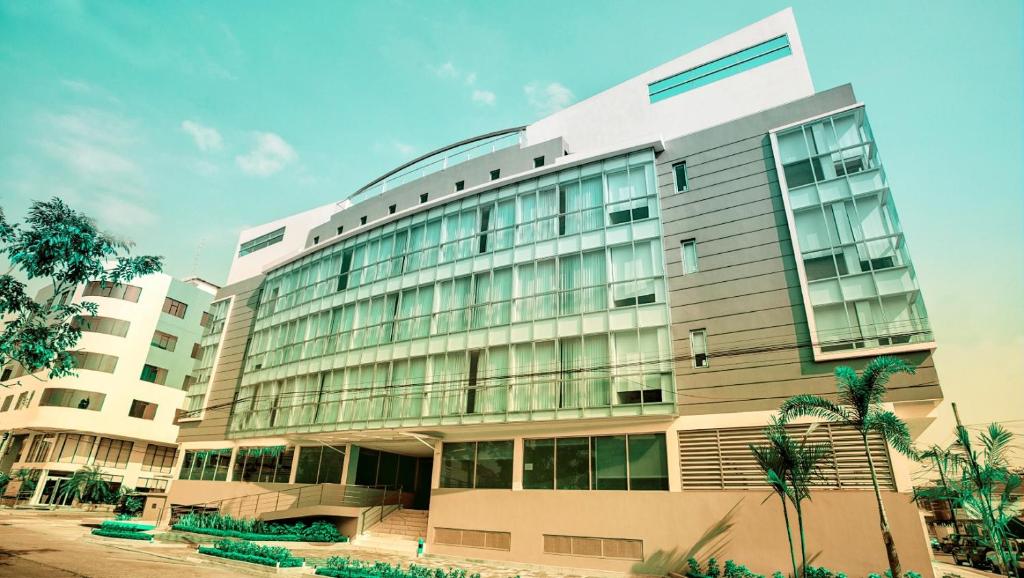 瓜亚基尔Hotel Puerto Pacifico Guayaquil Airport的一座大型建筑,设有玻璃窗,棕榈树