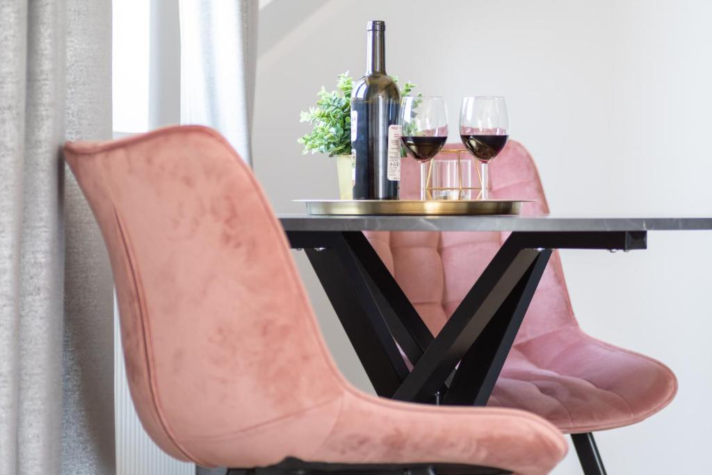 库瑞尼卡慕斯卡PORT 77的一张桌子,配有一张粉色椅子和两杯葡萄酒