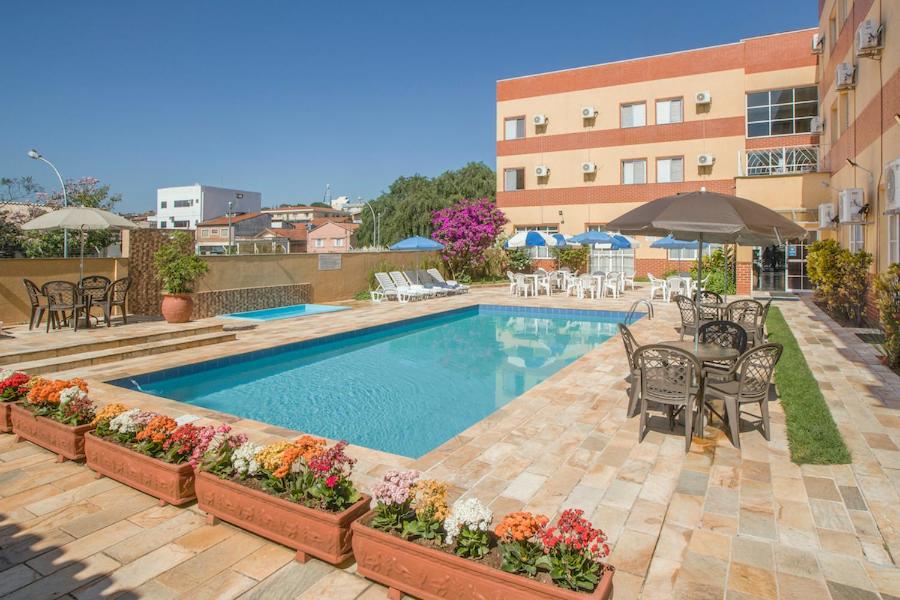阿蒂巴亚Itapetinga Hotel的一座带桌椅的游泳池位于酒店大楼旁