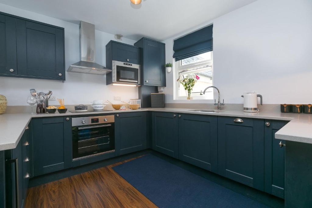 圣艾夫斯Will's Rock的厨房配有蓝色橱柜、水槽和窗户。