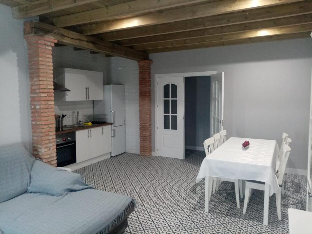 AljucénCasa Rural La Plata的一间带白色桌子的客厅和一间厨房