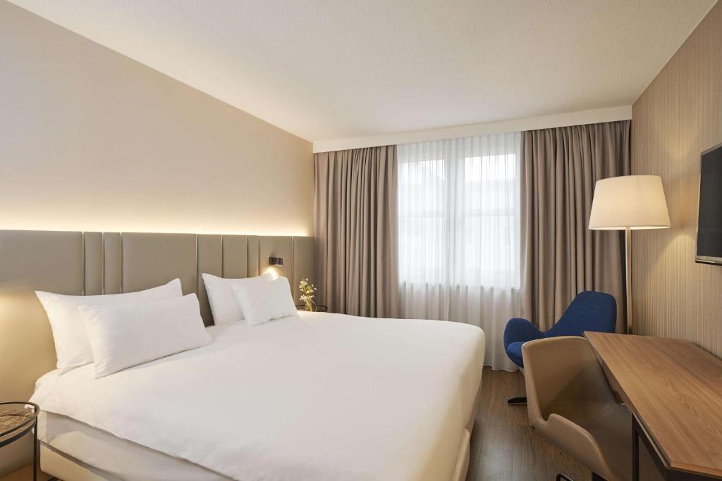 克尔斯特尔巴赫NH法兰克福机场酒店的酒店客房设有一张白色大床和一张书桌