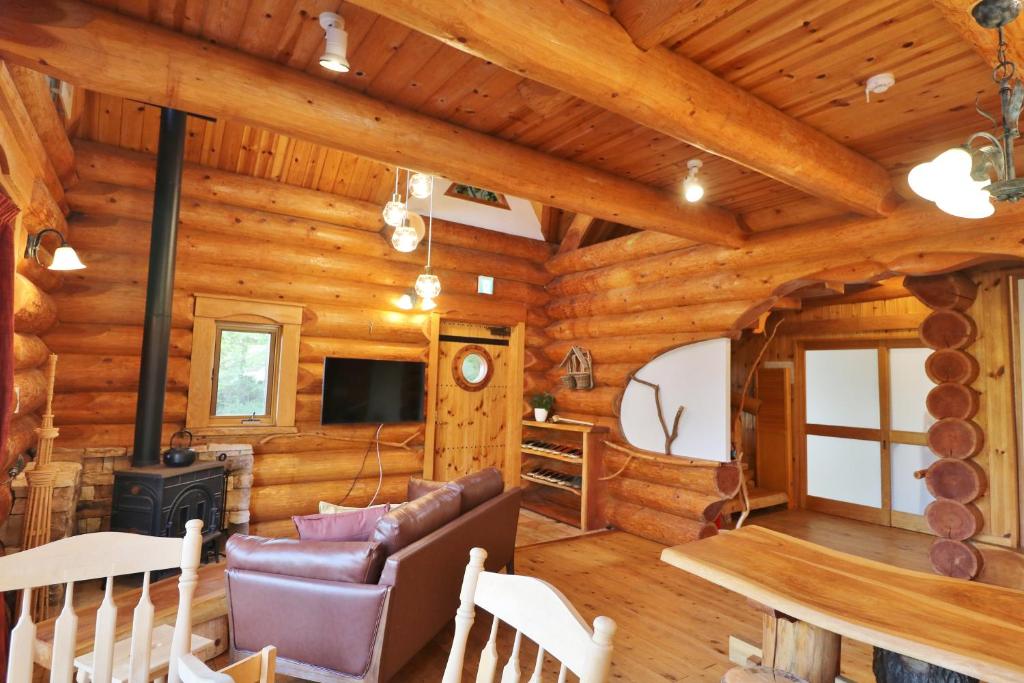 Futoログキャビン伊豆高原的小木屋客厅配有沙发和炉灶