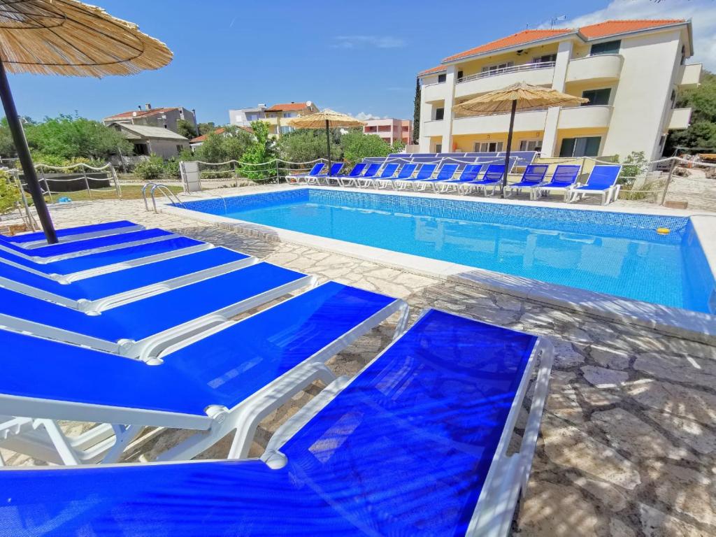 罗戈兹尼察Apartments CVITA Holiday的一个带蓝色椅子和遮阳伞的游泳池