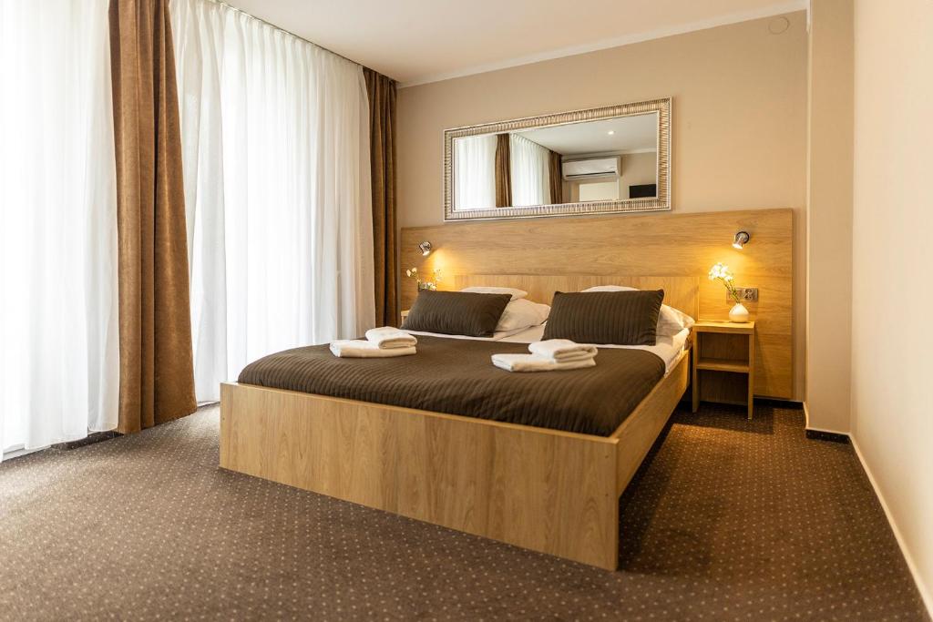 罗兹波什酒店的卧室配有一张大床,墙上装有镜子