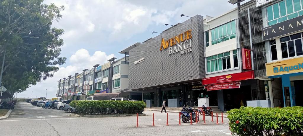 加影AVENUE BANGI HOTEL的城市街道上一排有停车车辆的建筑物