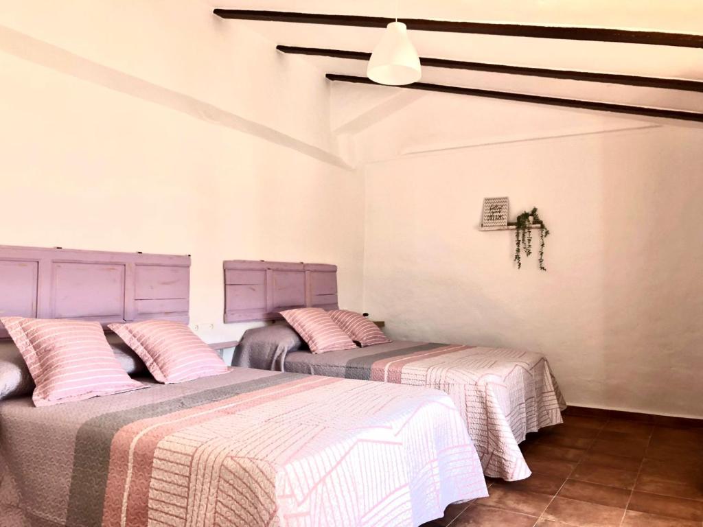 隆达Casa de campo con maravillosas vistas, bbq y piscina的配有粉红色和白色床单的客房内的两张床