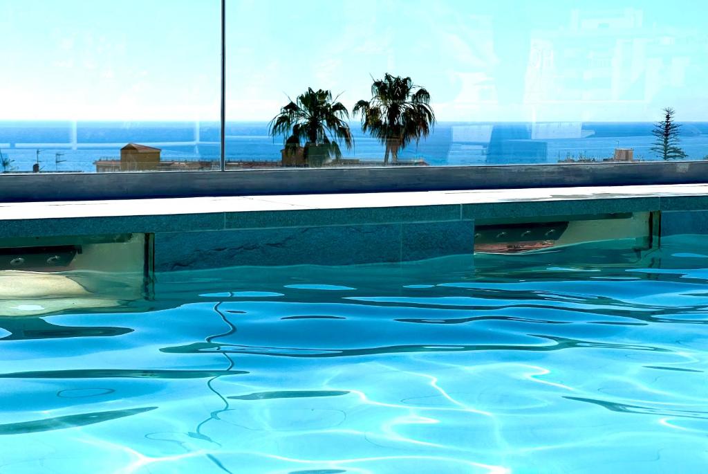 多列毛利诺斯Hotel Sireno Torremolinos - Adults Only, Ritual Friendly的一座拥有蓝色海水和棕榈树的游泳池