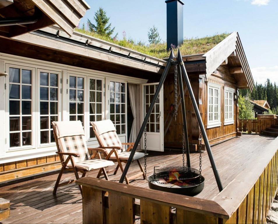 特吕西尔ReveEnka - cabin in Trysil with Jacuzzi for rent的一个带两把椅子和火坑的甲板