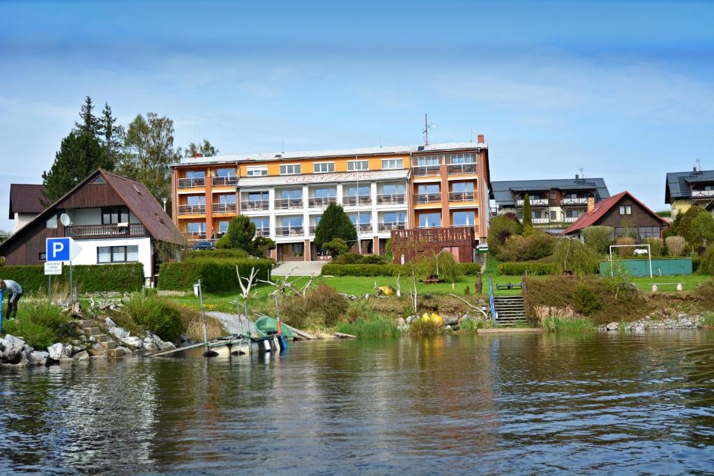 Dolní Vltavice卡拉旅馆的河边的一座建筑物,河岸上的人