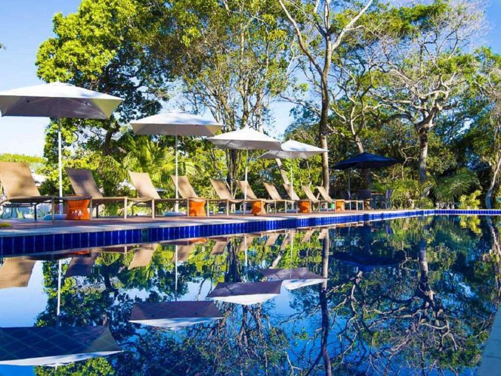 马塔迪圣若昂PRAIA DO FORTE ! Vilage de 80 m2 a 600 metros da vila的游泳池配有椅子、遮阳伞和水