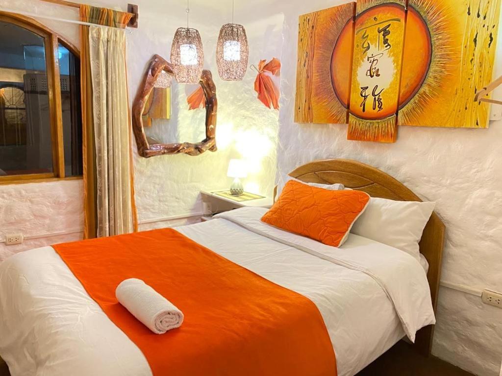 库斯科大地之母旅馆的一间卧室配有一张带橙色和白色毯子的床