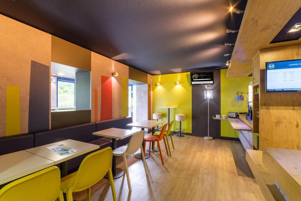 穆昂萨尔图B&B HOTEL Cannes Mouans Sartoux的餐厅拥有色彩缤纷的墙壁和桌椅