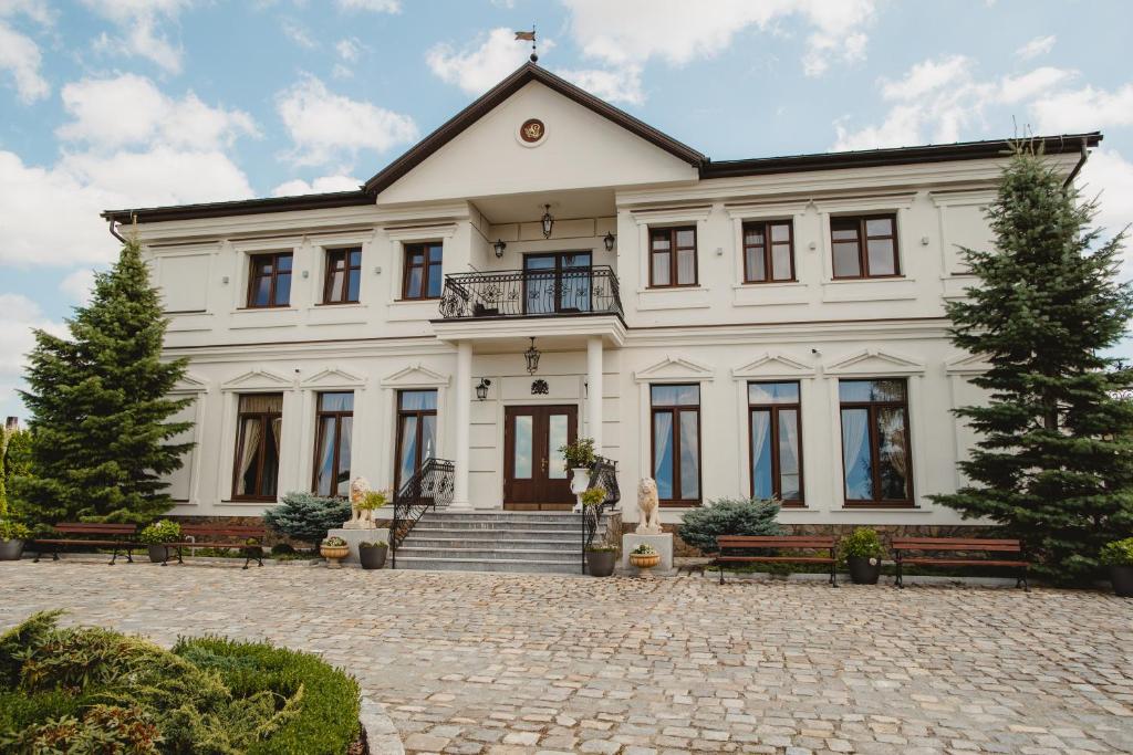 乌涅尤夫Pałac Uniejów的前面有长椅的大白色房子