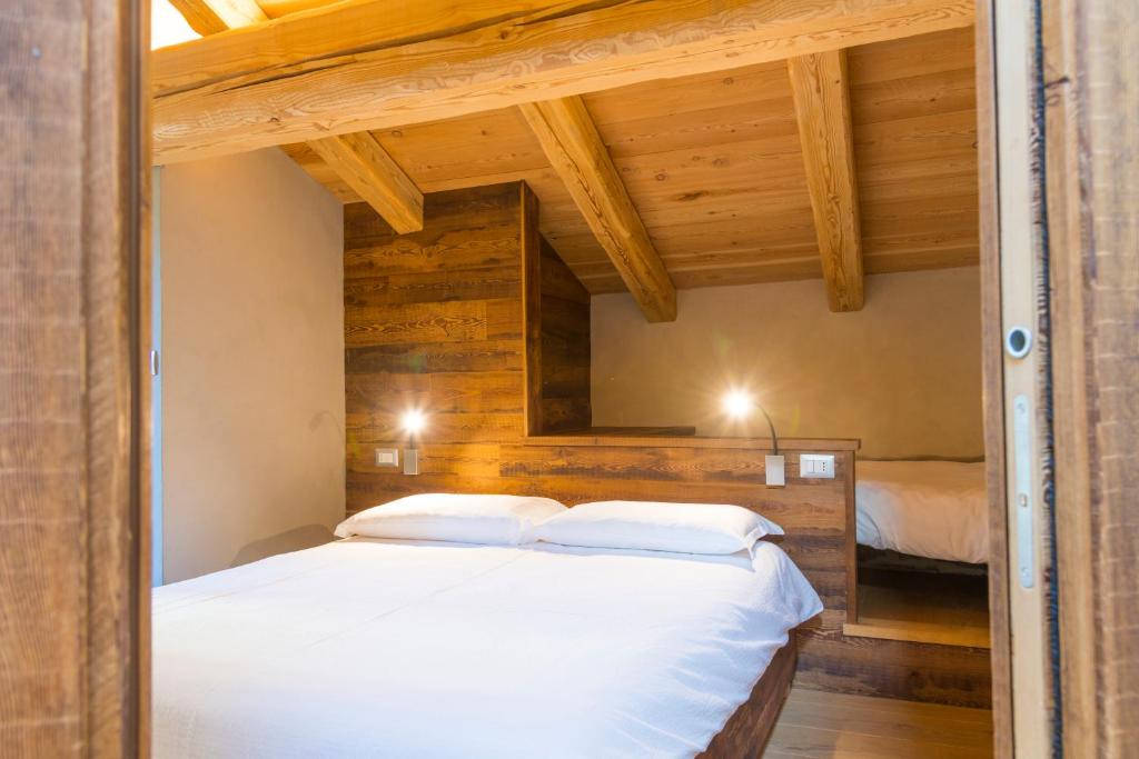 UsseauxLA PLACETTE - Albergo diffuso e Trattoria的卧室配有一张白色大床和木墙