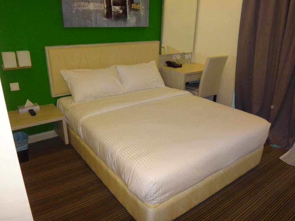 关丹科斯马商务酒店的卧室配有白色的床和2张桌子