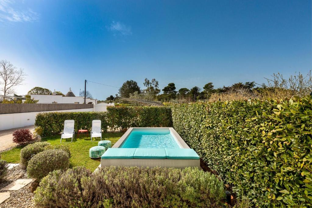 马丁纳弗兰卡I Colmi Trulli Suites by BarbarHouse的花园内的游泳池,配有两把椅子和树 ⁇ 