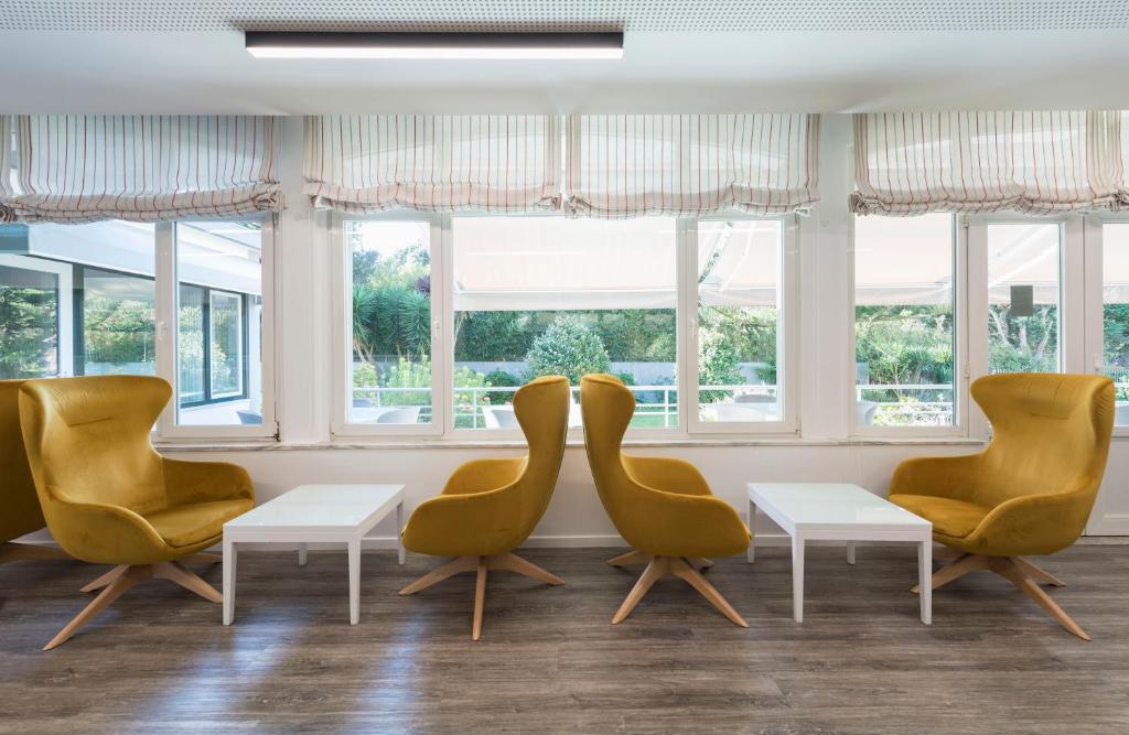 波瓦-迪瓦尔津瓦尔津酒店的一间设有黄色椅子和桌子的等候室,窗户