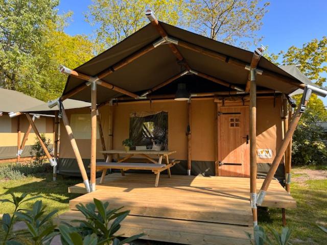 瑞斯Luxe Safaritent Medley 5 persoons op Camping Rijsterbos的木甲板上设有野餐桌的凉亭