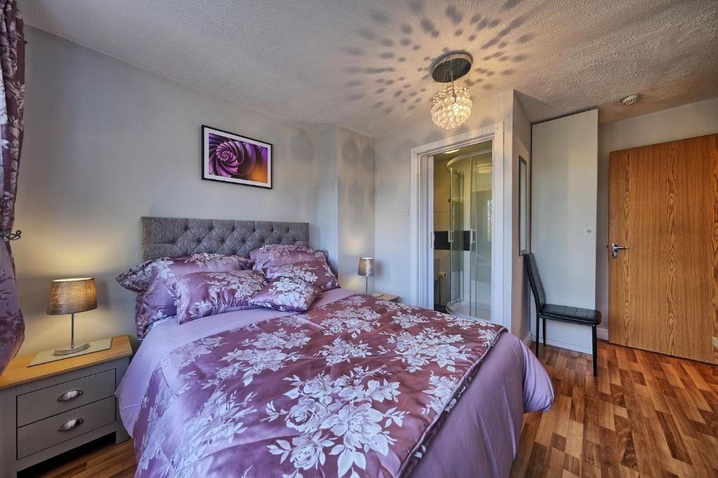 伯肯黑德Upton Village Guest House的一间卧室配有紫色的床和吊灯。