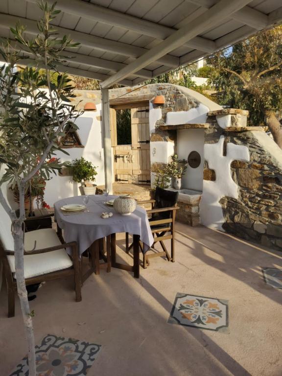 EpiskopianáRomantic sunset cycladic house in Sotires的庭院配有桌椅和石炉。