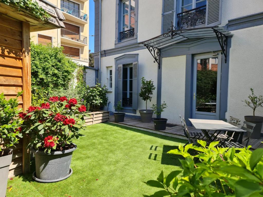 特鲁瓦La Maison V.H., Appartements d'Hôtes的一座种有红色花卉和桌子的小花园
