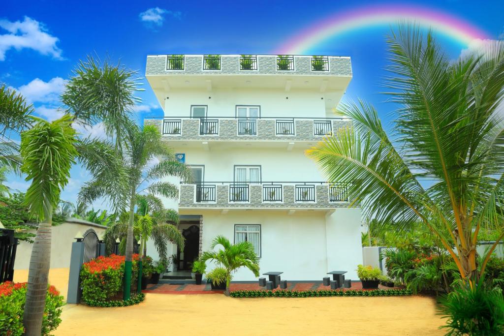 亭可马里Blue Diamond Resort的一座白色的大建筑,天空中有一个彩虹