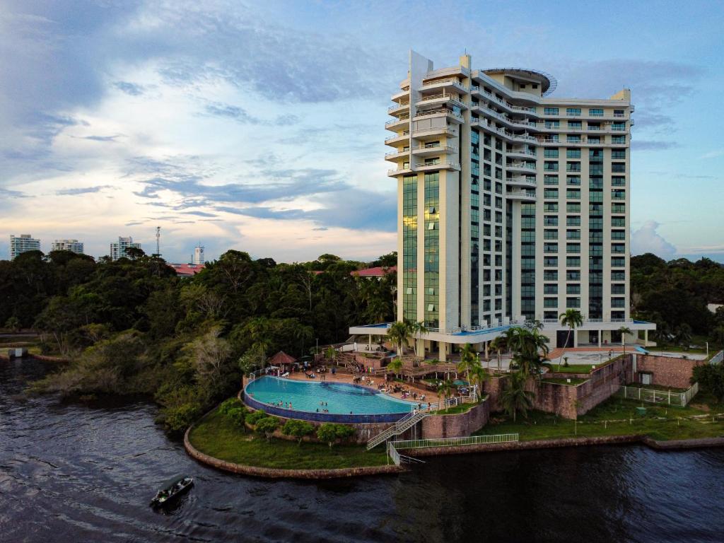 马瑙斯Tropical Executive Hotel的一座大型建筑,设有游泳池,毗邻河流