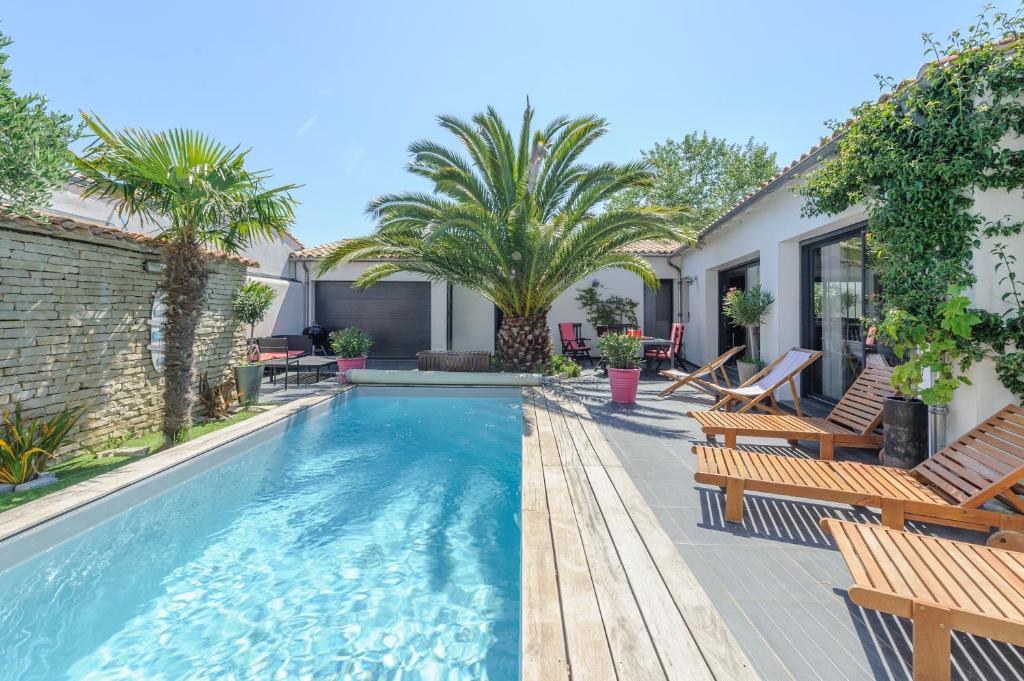 滨海拉库阿尔德Villa Lizelya的后院的游泳池,设有椅子和棕榈树