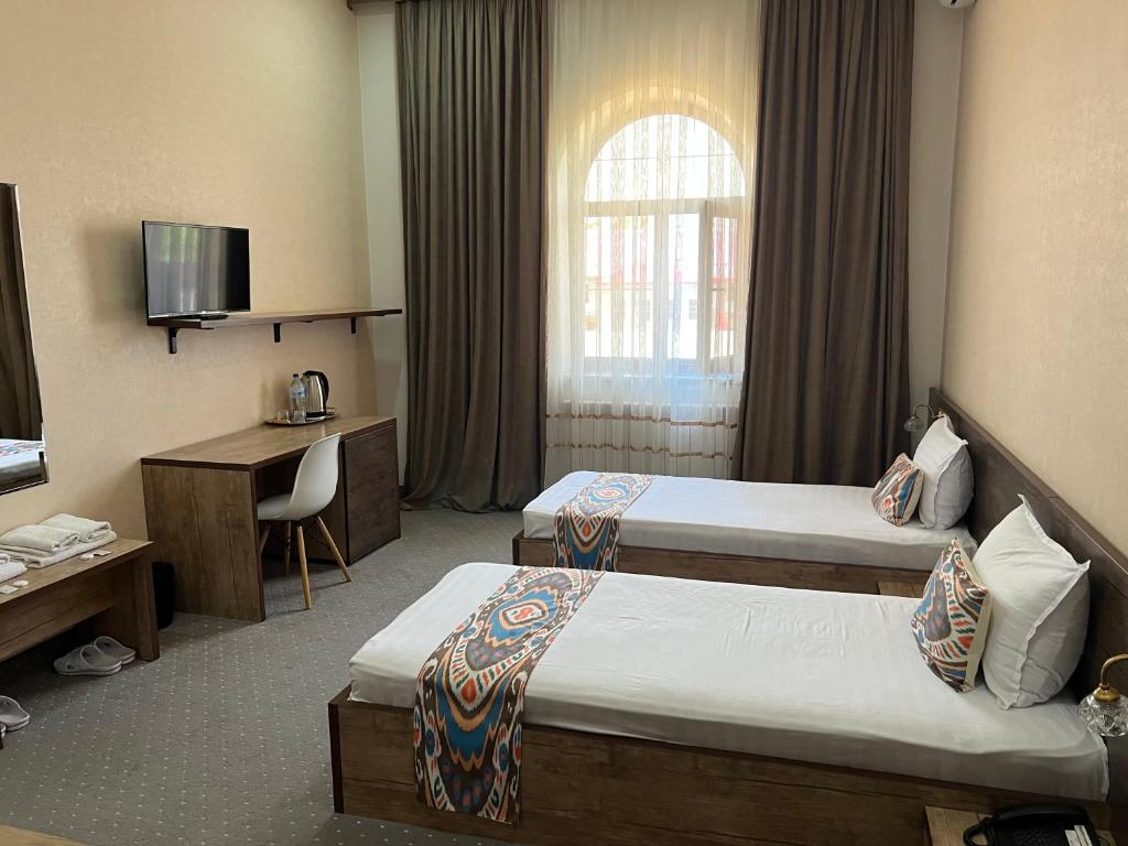 撒马尔罕Mahmud Hotel的酒店客房配有两张床和一张书桌