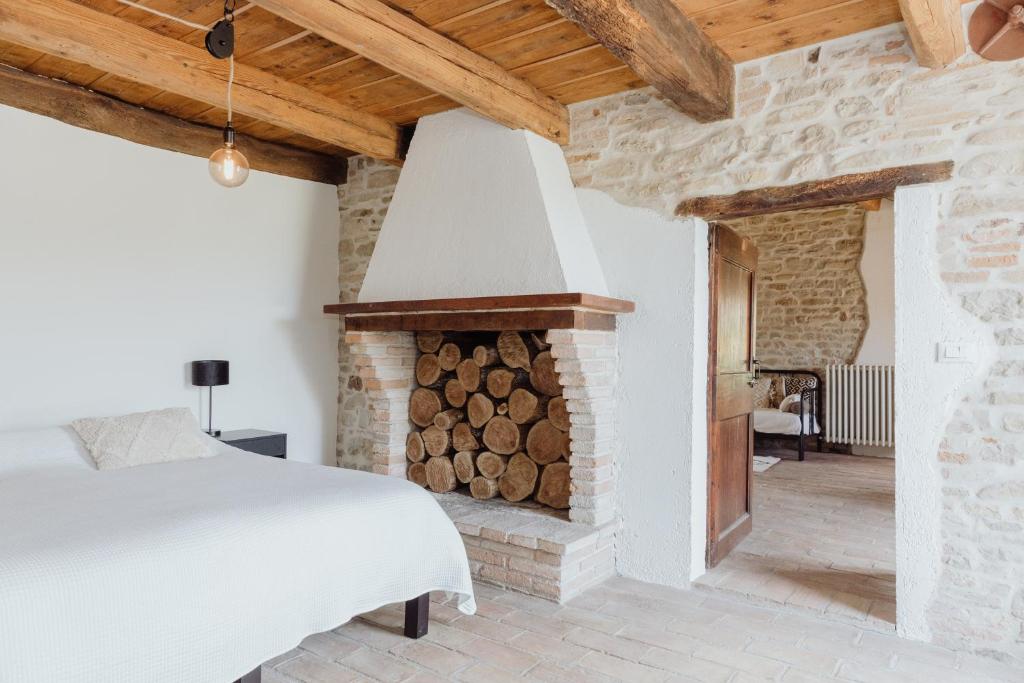 蒙特罗伯托Agriturismo Qui Voglio的一间卧室配有一张床和一个壁炉及木柴
