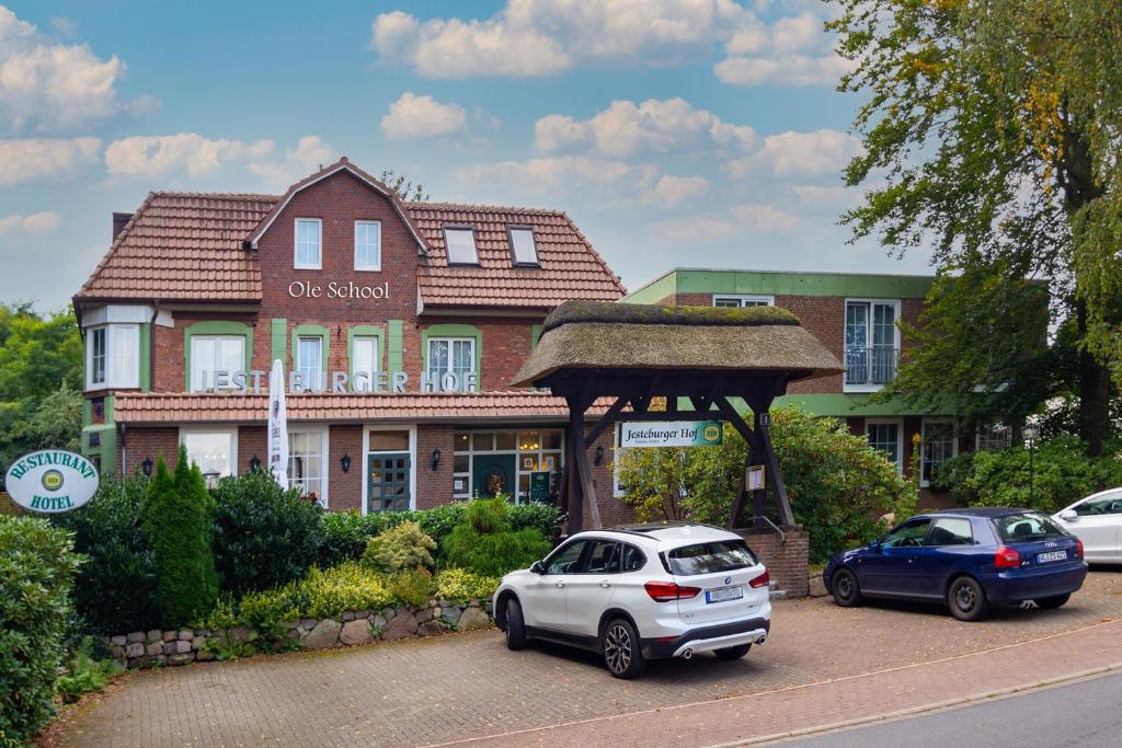 杰斯帝堡耶斯特伯格霍夫酒店的两辆汽车停在房子前面的停车场