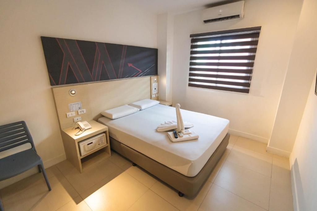 马尼拉Wow Budget Hotel Cubao的一间小卧室,配有白色的床和窗户