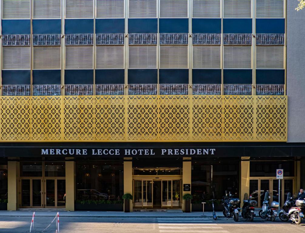 莱切Mercure Hotel President Lecce的一座大型建筑,外面停有摩托车