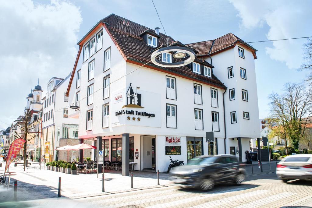 图特林根Hotel Stadt Tuttlingen的开车经过街上的白色建筑