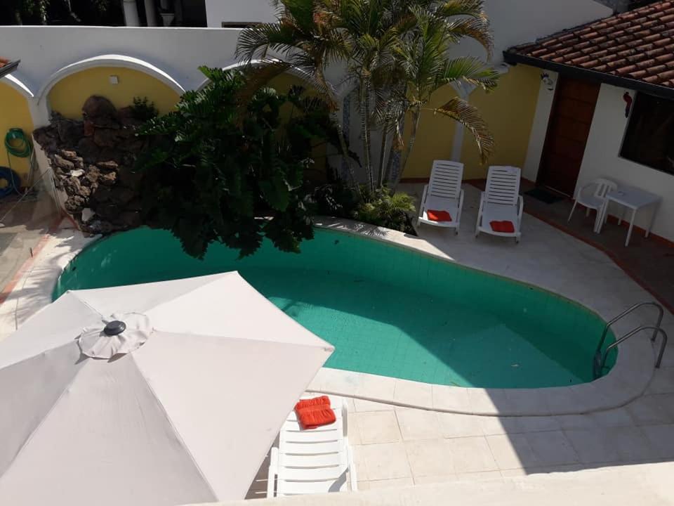 亚松森Hotel Casa Jardin的一个带白色遮阳伞和椅子的游泳池