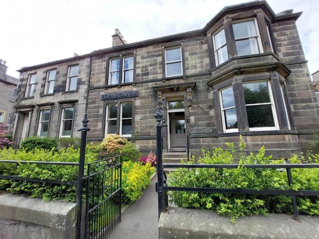 爱丁堡Edinburgh House Hotel的一座古老的石头建筑,前面有黑色的围栏