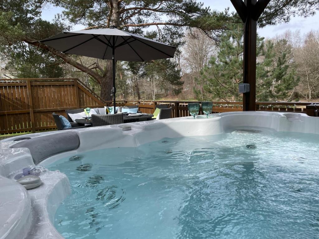 皮特洛赫里Luxury Riverside Lodge, Blair Atholl的后院的带遮阳伞的热水浴池