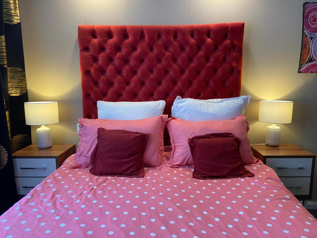 巴克乌Garsoniera Riviera的一张带红色床头板和粉红色枕头的床