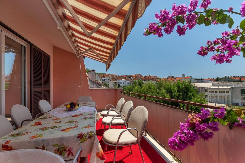 马卡尔斯卡Apartments Roza的阳台配有桌椅和紫色鲜花