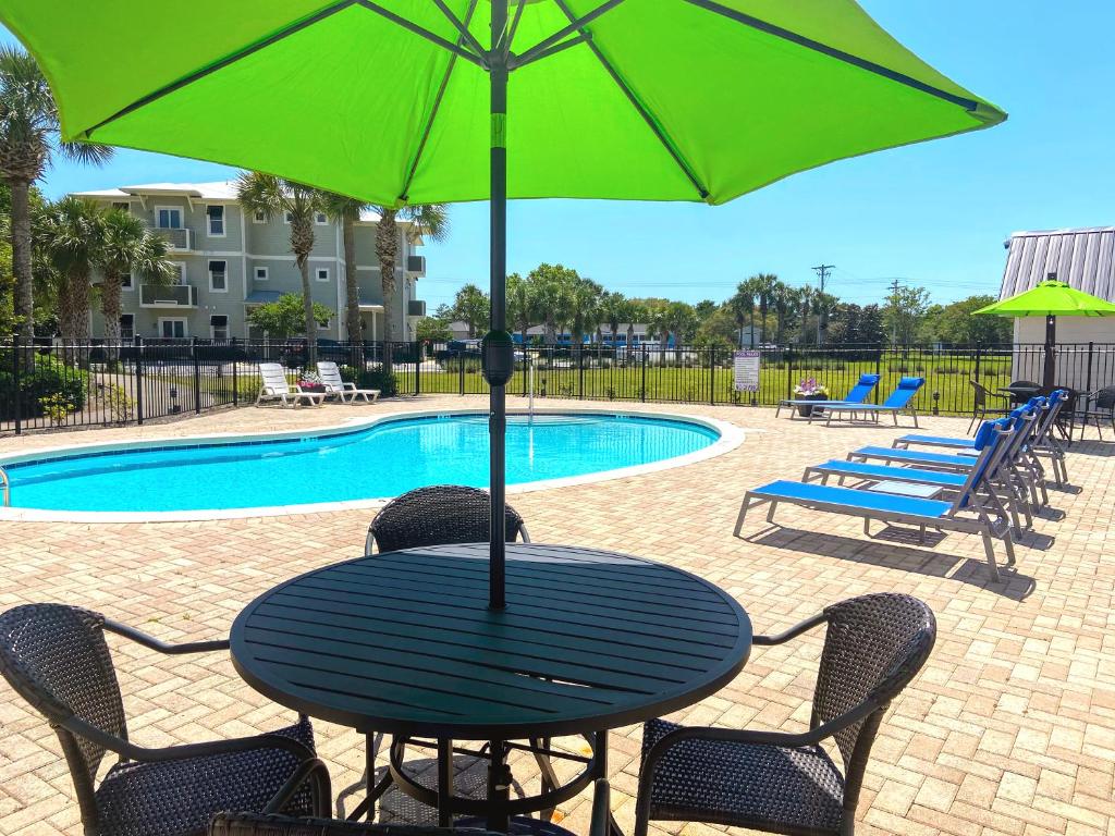 圣罗莎海滩30-A Inn & Suites的一张桌子,旁边是一把绿色遮阳伞