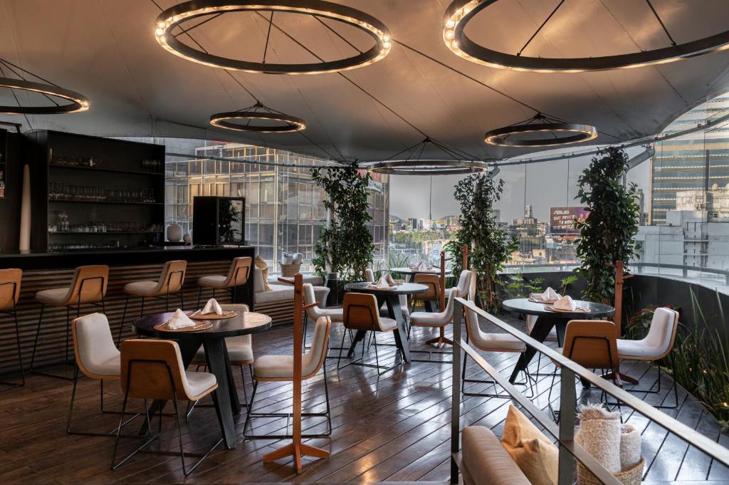 墨西哥城金宝套房酒店的餐厅设有桌椅和大窗户。