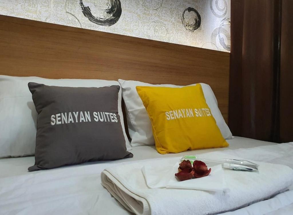 雅加达SENAYAN SUITES的一张带两个枕头的床和一盘食物