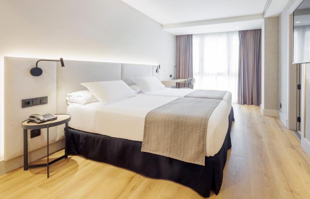 圣塞瓦斯蒂安Hotel Ilunion San Sebastián的酒店客房设有一张大床和一张桌子。